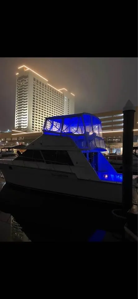 Slide: The Image of 1990 Silverton 40 Convertible yacht with blue lights docked at night near a lit building. - 12
