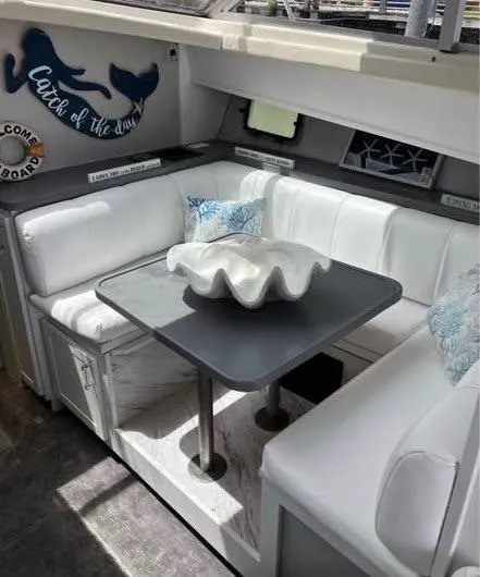 Slide: The Image of Interior of 1990 Silverton 40 Convertible yacht with white seating and decorative shell centerpiece. - 9