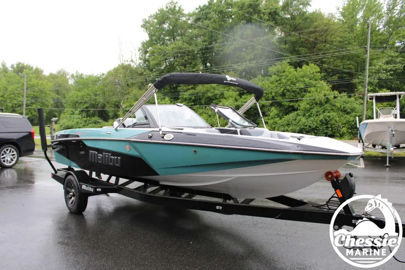 Slide: The Image of 2024 Malibu TXi Mo boat on trailer, parked outdoors on a rainy day. - 27