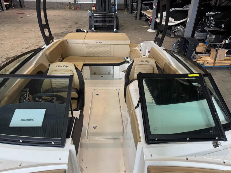 Slide: The Image of 2024 Sea Ray 230SPX boat interior with tan seating and black accents in a showroom. - 14