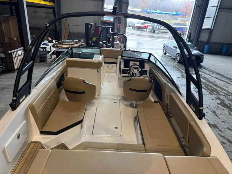 Slide: The Image of 2024 Sea Ray 230SPX boat interior with beige seating and black accents in a warehouse. - 9
