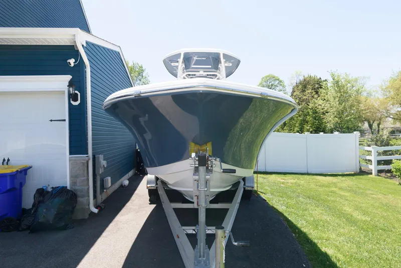Slide: The Image of 2016 Tidewater 230 CC Adventure boat on trailer beside blue house. - 3