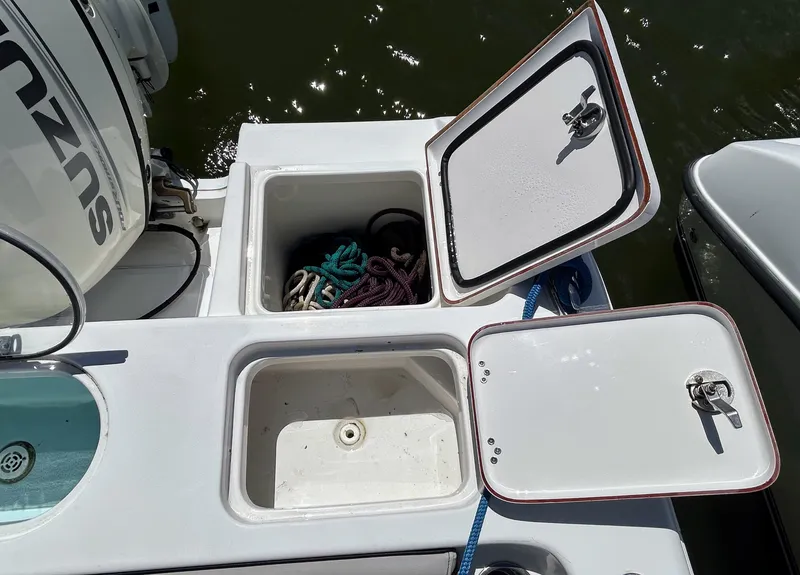 Slide: The Image of 2017 Sea Pro 219 Center Console boat storage compartments with open hatches and visible ropes. - 9