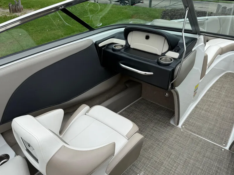 Slide: The Image of 2018 Crownline 235 SS boat interior with beige and black seating, dashboard, and cup holders. - 11