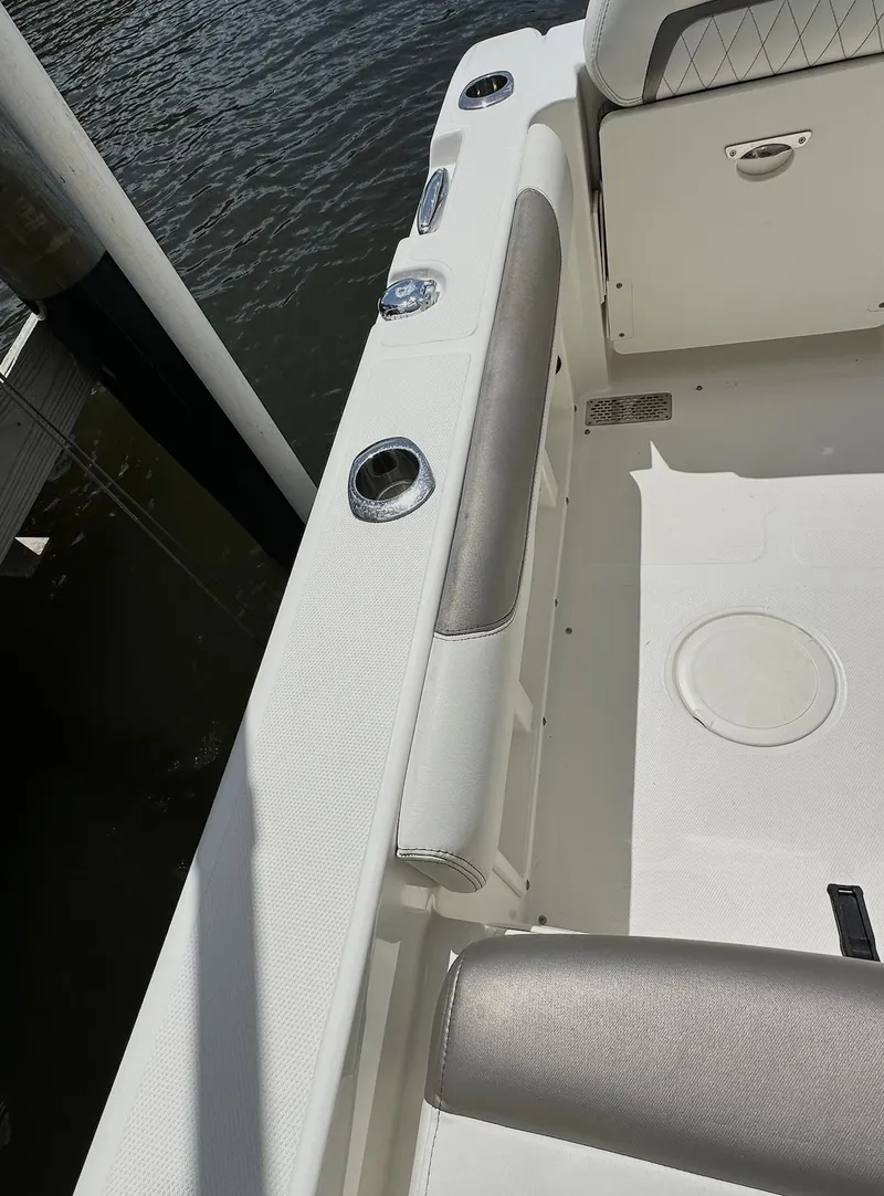 Slide: The Image of 2021 World Cat 255 DC boat interior with cushioned seating and cup holders by the water. - 42