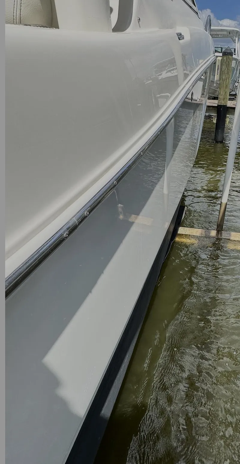 Slide: The Image of 2021 World Cat 255 DC boat docked, side view, reflecting on water. - 44