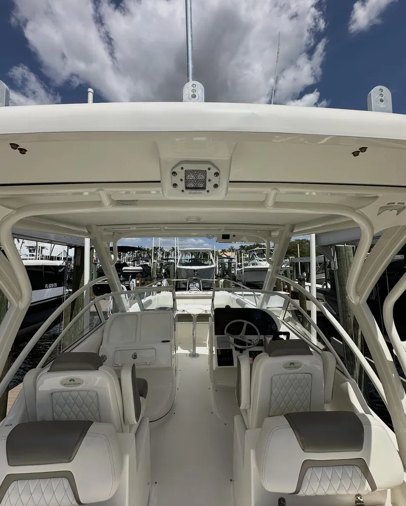 Slide: The Image of 2021 World Cat 255 DC boat interior with seating and steering, docked under a cloudy sky. - 45