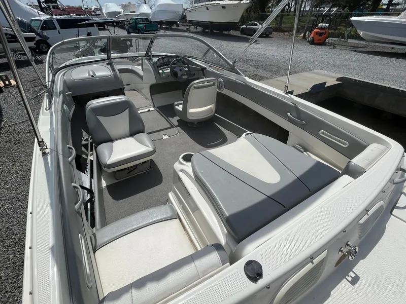 Slide: The Image of 2011 Bayliner 195 boat interior with seating and steering wheel, parked on gravel. - 12