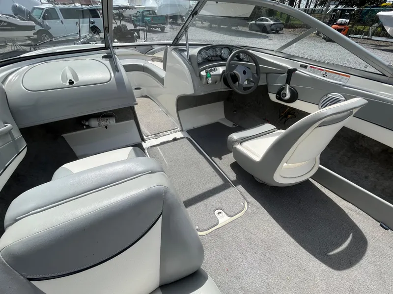 Slide: The Image of 2011 Bayliner 195 boat interior with gray seating and steering wheel, showcasing spacious design. - 13