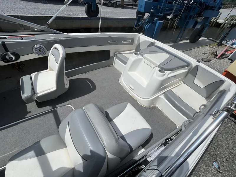 Slide: The Image of 2011 Bayliner 195 boat interior with gray and white seating, docked outdoors. - 14