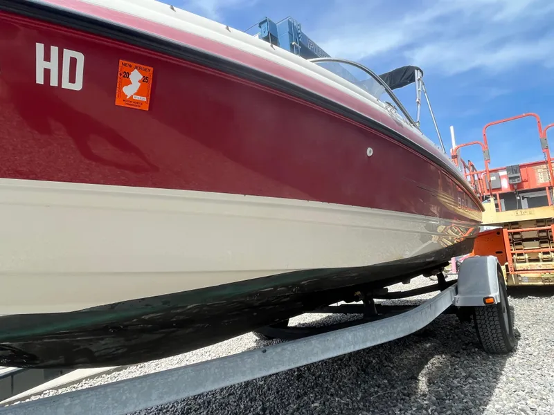 Slide: The Image of 2011 Bayliner 195 boat on trailer, red and white hull, sunny day. - 2