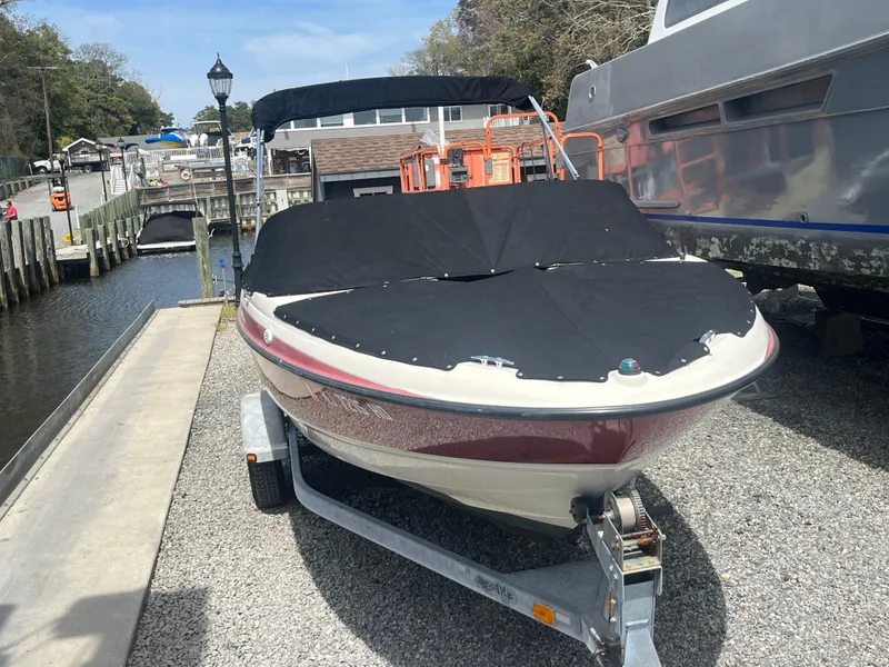 Slide: The Image of 2011 Bayliner 195 boat on trailer, covered, parked near a dock. - 27