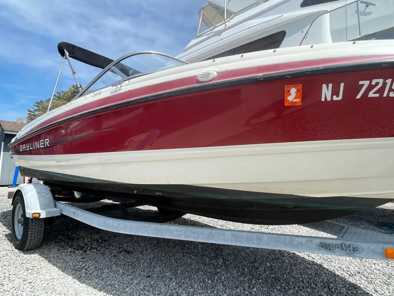 Slide: The Image of 2011 Bayliner 195 boat on trailer, red and white, parked on gravel. - 4