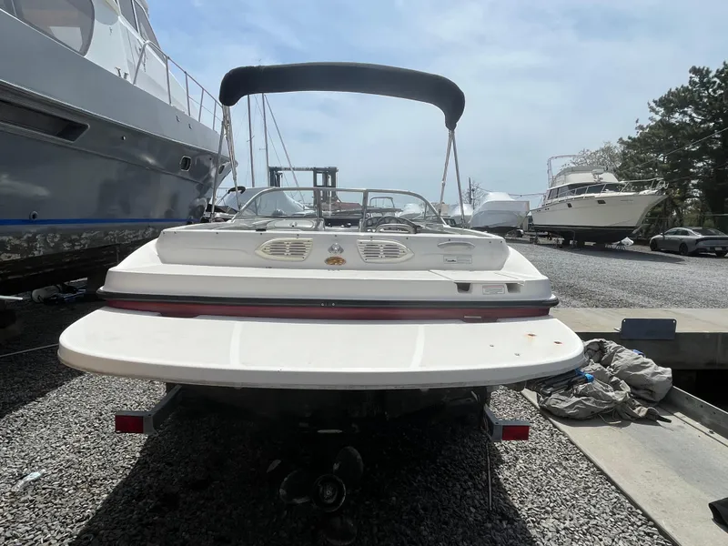 Slide: The Image of 2011 Bayliner 195 boat with canopy, parked on gravel near other boats. - 8