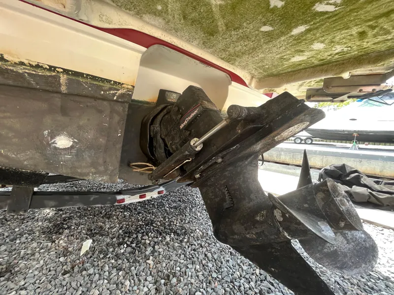 Slide: The Image of 2011 Bayliner 195 boat underside showing propeller and drive system on gravel surface. - 9