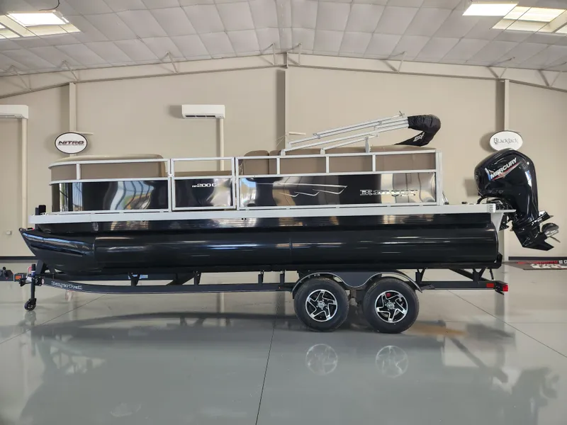 The Image of 2025 Ranger 200C pontoon boat in showroom, black exterior, dual-axle trailer, outboard motor. - 0
