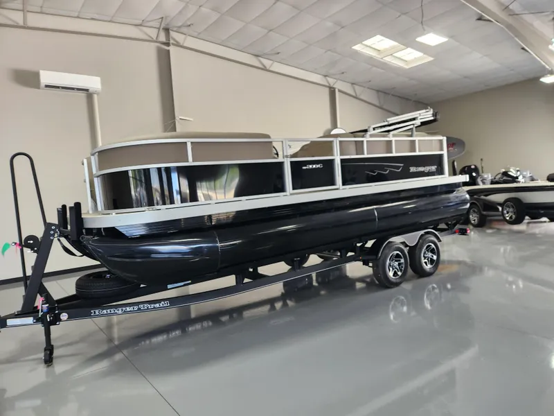 Slide: The Image of 2025 Ranger 200C pontoon boat on trailer in showroom, sleek black design. - 1