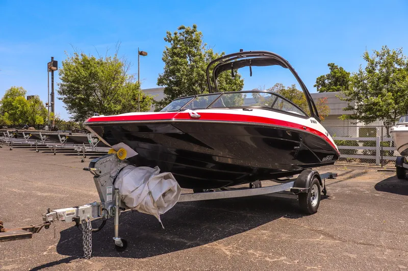 The Image of 2025 Yamaha Boats AR195 on trailer, sleek design, black and red accents, outdoor setting. - 1