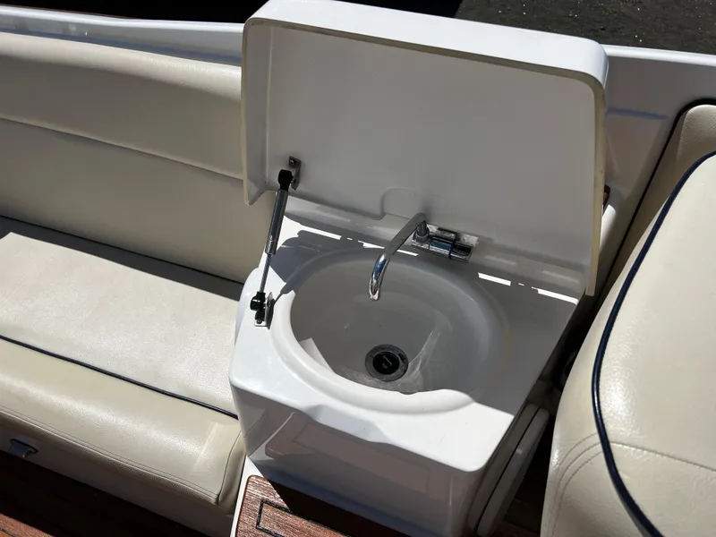 Slide: The Image of 2004 Chris-Craft Corsair 25 boat sink with open lid and seating area. - 11