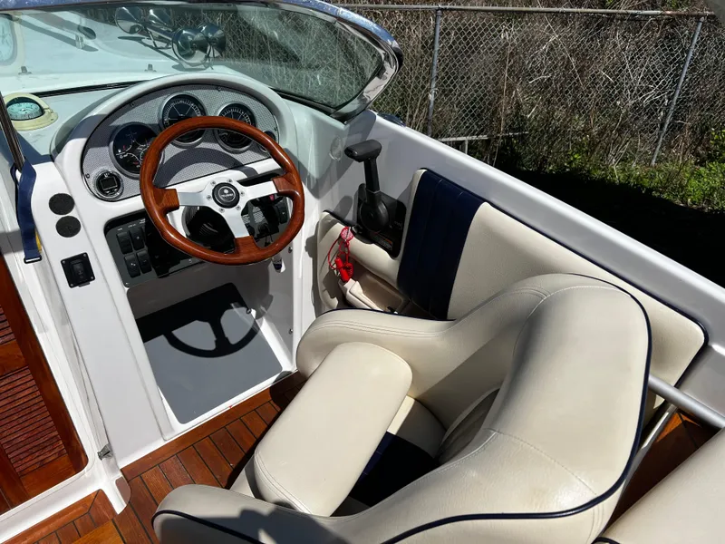 Slide: The Image of 2004 Chris-Craft Corsair 25 boat interior with wooden steering wheel and leather seating. - 7