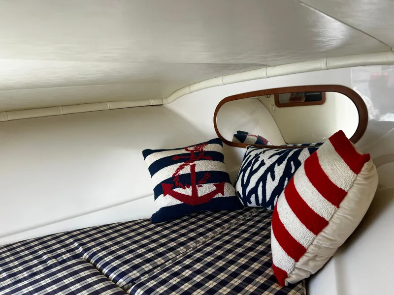 Slide: The Image of 2004 Chris-Craft Corsair 25 cabin interior with nautical-themed pillows and plaid bedding. - 9