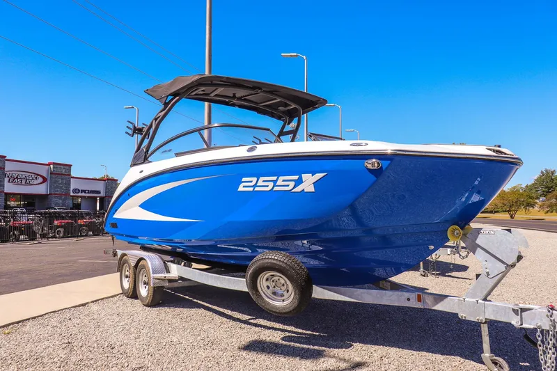 The Image of 2025 Yamaha Boats 255XD in blue on trailer, displayed outdoors. - 1