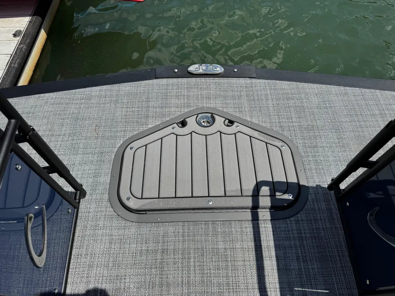 Slide: The Image of 2025 JC Neptoon Sport 23TT DSL boat deck with storage hatch, docked by water. - 6