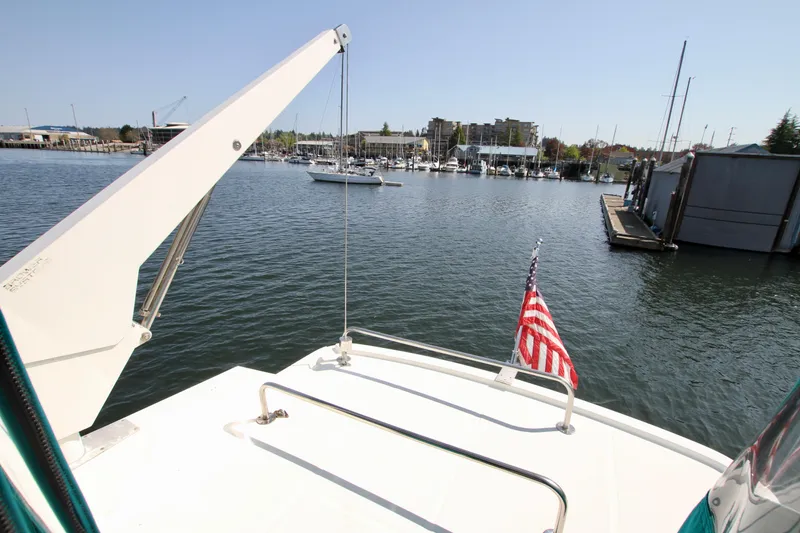 Slide: The Image of 1999 McKinna 47 Sedan yacht on calm waters with American flag, marina in background. - 12