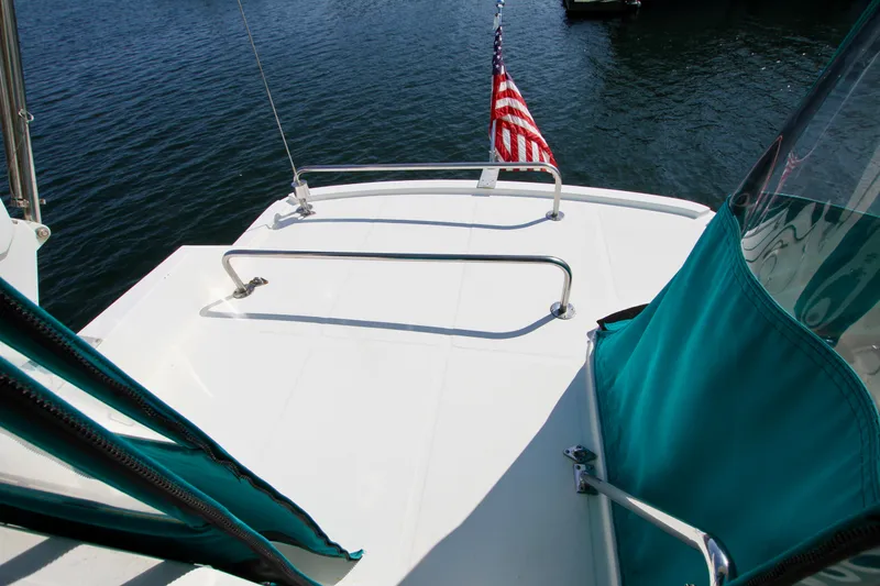 Slide: The Image of 1999 McKinna 47 Sedan yacht deck with American flag, teal accents, and railing. - 17