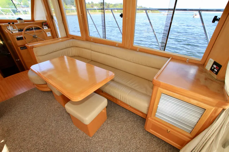 Slide: The Image of 1999 McKinna 47 Sedan interior with beige seating and wooden table by large windows. - 20
