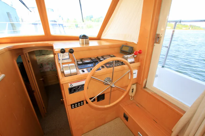 Slide: The Image of 1999 McKinna 47 Sedan yacht helm with wooden steering wheel and control panel. - 23