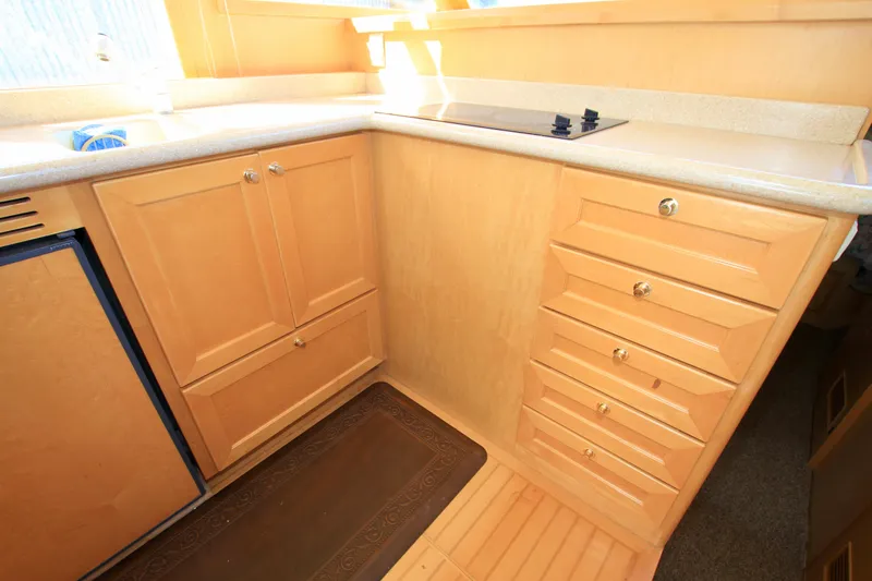 Slide: The Image of 1999 McKinna 47 Sedan yacht kitchen with wooden cabinets and countertop. - 24