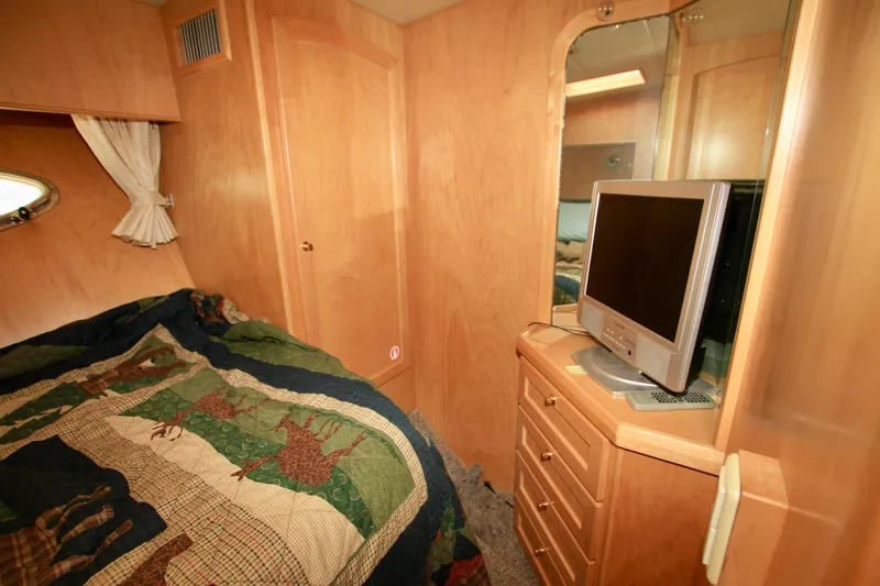 Slide: The Image of 1999 McKinna 47 Sedan cabin interior with bed, TV, and wooden cabinetry. - 27