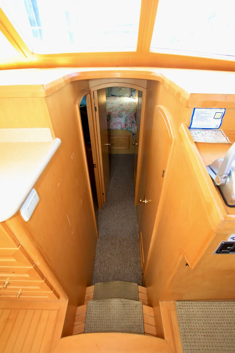Slide: The Image of Interior view of 1999 McKinna 47 Sedan yacht, featuring wooden cabinetry and carpeted hallway. - 30