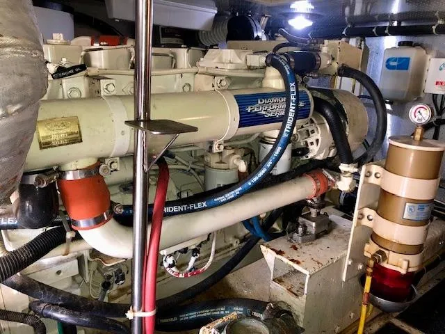 Slide: The Image of Engine room of a 1999 McKinna 47 Sedan yacht, showcasing complex machinery and hoses. - 43