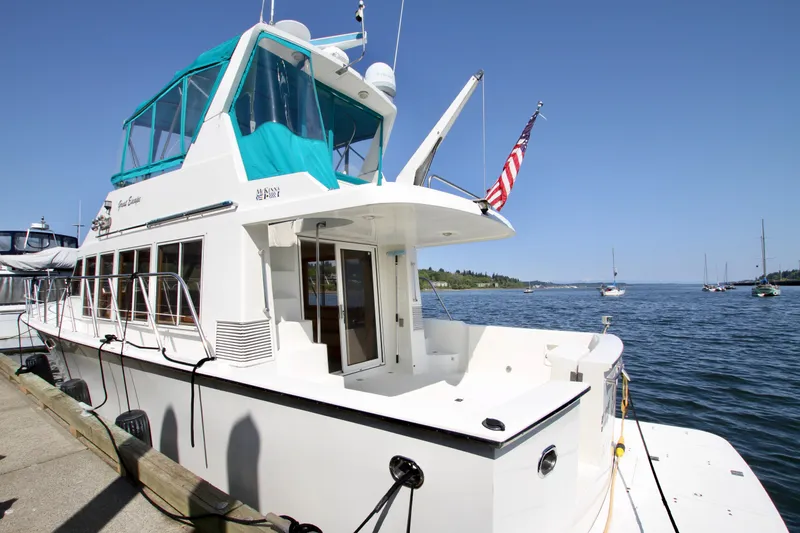 Slide: The Image of 1999 McKinna 47 Sedan yacht docked by the water, featuring a sleek design and American flag. - 7
