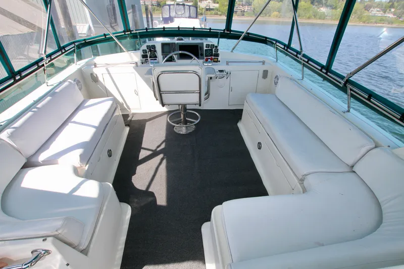 Slide: The Image of 1999 McKinna 47 Sedan yacht interior with white seating and helm, overlooking water. - 8