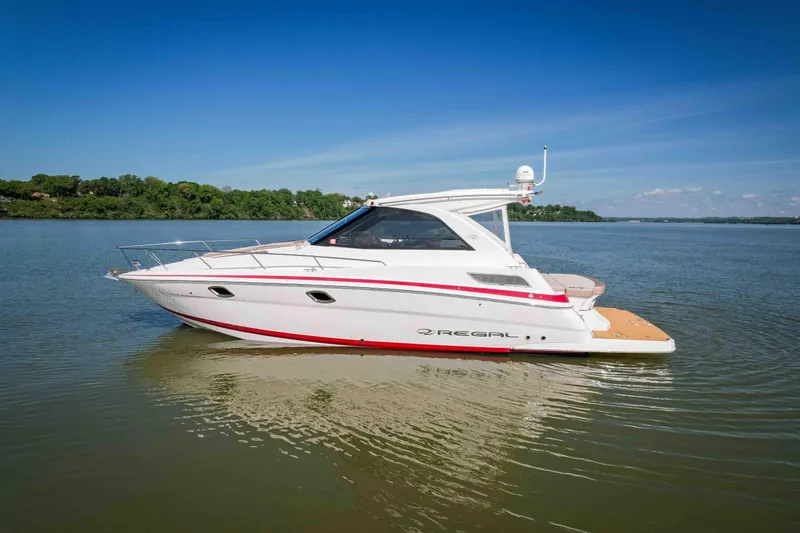 Slide: The Image of 2015 Regal 35 Sport Coupe boat on calm water under clear blue sky. - 13