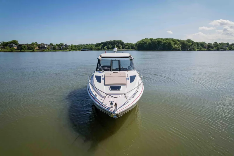 Slide: The Image of 2015 Regal 35 Sport Coupe on calm lake with lush green shoreline. - 2
