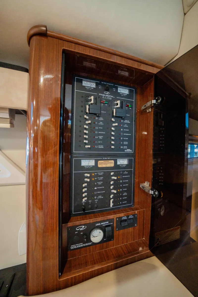 Slide: The Image of Electrical panel inside a 2015 Regal 35 Sport Coupe, featuring wood trim and control switches. - 34
