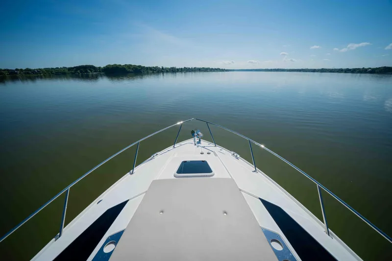 Slide: The Image of Bow view of 2015 Regal 35 Sport Coupe on calm lake under clear sky. - 35