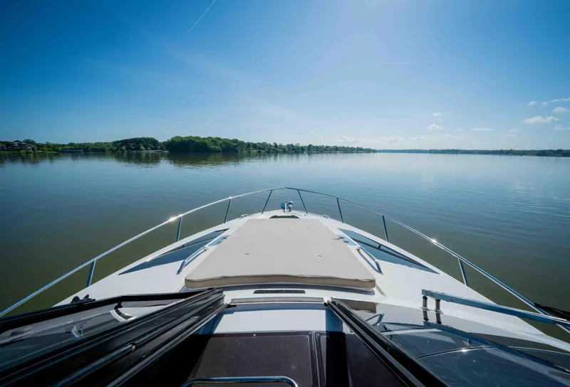 Slide: The Image of 2015 Regal 35 Sport Coupe cruising on a serene lake under a clear blue sky. - 38