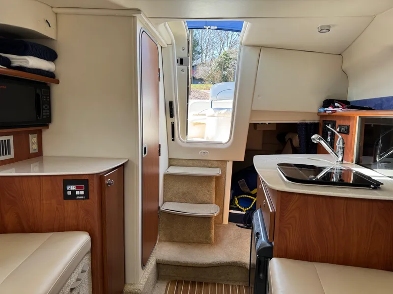 Slide: The Image of Interior of a 2008 Bayliner 265SB boat, featuring a compact kitchen and seating area. - 14