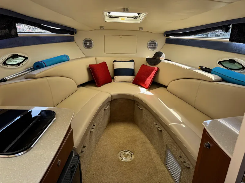 Slide: The Image of Interior of a 2008 Bayliner 265SB boat with beige seating and colorful cushions. - 9