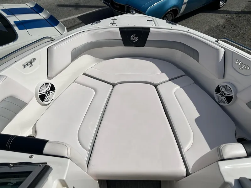 Slide: The Image of 2019 Chaparral 23 H2O Surf boat interior with white cushioned seating and speakers. - 15