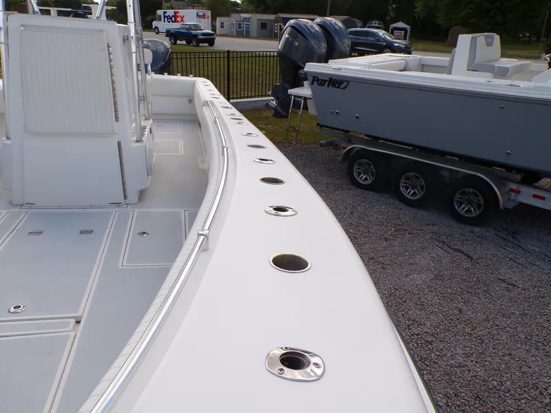 Slide: The Image of 2002 Contender 31 Center Console boat with rod holders, parked on gravel near another boat. - 16