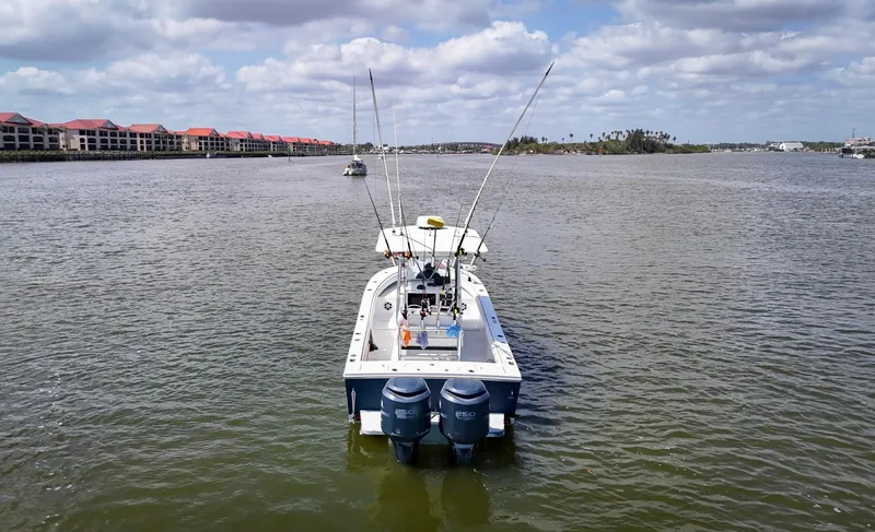Slide: The Image of 2006 Regulator 26 FS boat on calm water with fishing rods and twin engines. - 5