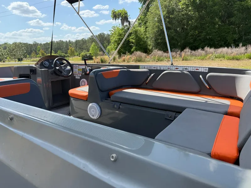 Slide: The Image of 2019 Bayliner Element E21 boat interior with gray and orange seating, scenic outdoor backdrop. - 3