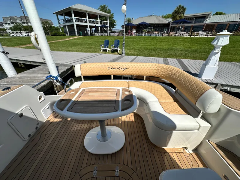 Slide: The Image of 2007 Chris-Craft Roamer 40 yacht deck with elegant seating and table, docked near waterfront homes. - 11