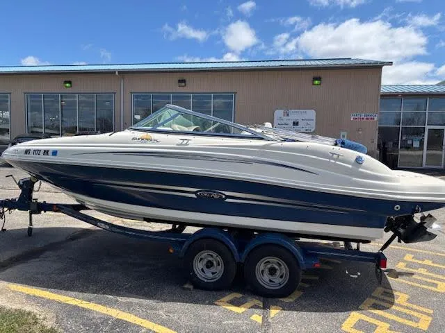 Slide: The Image of 2007 Sea Ray 200 Sundeck boat on trailer, parked outside a building under a blue sky. - 8